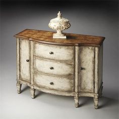 an antique white dresser with drawers and a vase on it's top, against a gray background