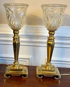 two glass candlesticks sitting on top of a wooden table