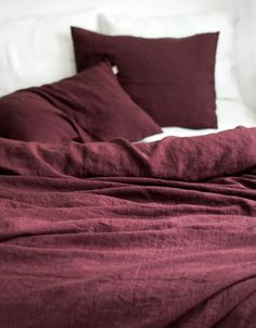 an unmade bed with red linens and pillows