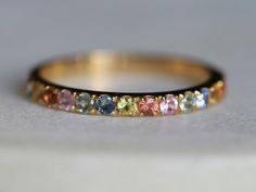 a yellow gold band with multi colored stones