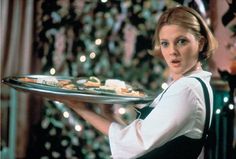 a woman holding a tray with food on it in front of a christmas tree and lights