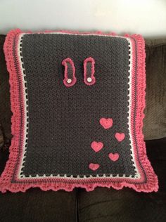 a crocheted pillow with scissors and hearts on the front is sitting on a couch