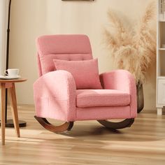 a pink rocking chair sitting on top of a hard wood floor