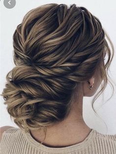 a woman with long hair in a low bun braided into an up - do