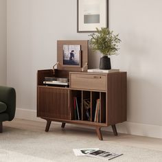 a living room with a green chair and a wooden cabinet in front of a white wall