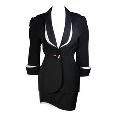 This fabulous Thierry Mugler ensemble is comprised of medium weight wool gabardine with a dramatic sculpted white lapel and cuff detail in white satin. Fitted waist has a single Tri-color abstract square button echoing the white edges of the lapels and cuffs. Medium density shoulder pads. Fitted skirt with a hidden zipper and covered satin snap at back with 3-D white detail at the hem. In overall excellent condition. There is a minute chip at the corner of the white edge of the button. Fully lined in a silk like polyester. Size 42 Please review the measurements provided to ensure a perfect fit. Jacket- Shoulders:17 inches Sleeve:20 inches Bust:38 inches Waist:29 inches Hips:40 inches Skirt- Waist:28 inches Hips: 38 inches Length: 17.25 inches White Skirt Suit, Mugler Black, Suits Outfits, Versace Pink, Bustle Skirt, Future Clothes, Skirt Suit Set, Yellow Skirt, Black And White Skirt