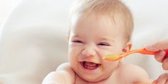 a baby is sitting in a high chair and eating from a spoon with his mother's hand