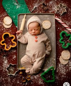 a baby is laying in a pan with cookies and pretzels