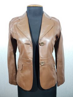 Stylish women's brown leather jacket. A simple brown leather jacket. The jacket is made of durable soft brown genuine leather. The jacket fastens with plastic buttons. The jacket has two convenient false pockets down in the form of flaps with a button. There are decorative strips with a button on the back of the belt. The jacket has a pleasant polyester lining. The jacket is stylish, elegant and comfortable to wear, it will perfectly emphasize your unique image and warm the cool weather. MEASUREMENTS Length                                56 cm  |  22 in Pit to pit                              45 cm  |  17.5 in Chest circumference           90 cm  |  35.5 in Waist circumference            80 cm |  31.5 in Bottom circumference         90 cm |  35.5 in   Shoulders                            4 Fitted Brown Leather Jacket With Buttons, Brown Leather Single-breasted Blazer, Brown Leather Outerwear With Buttons, Brown Leather Jacket With Buttons For Winter, Brown Leather Jacket With Buttons For Fall, Brown Leather Single-breasted Outerwear, Brown Leather Jacket With Button Closure For Work, Womens Long Leather Jacket, Taupe Leather Jacket