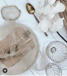 the table is set with white flowers and silverware