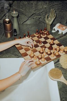 a woman is playing chess on a table with other items around her, including brush and comb