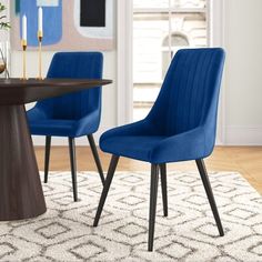 two blue chairs sitting on top of a rug next to a wooden table and chair