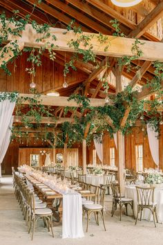 an indoor venue with tables and chairs covered in greenery