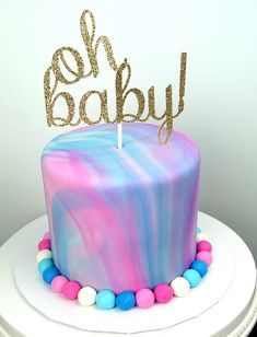 a pink and blue marbled cake with the word baby on top