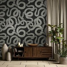 a black and white wallpaper with an abstract design in the middle is next to a plant