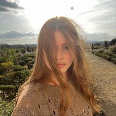 a woman with long hair standing on a path