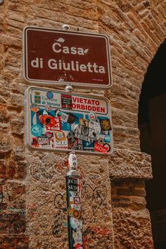 a street sign on the side of a building that has graffiti all over it and is covered in stickers