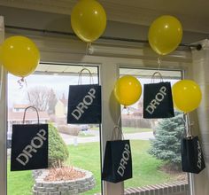 balloons are hanging from the ceiling in front of a window with drop drop bags on it