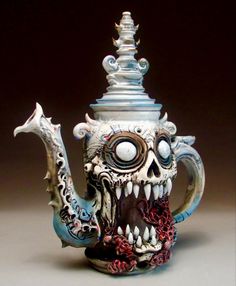 a ceramic teapot with a skull face on it