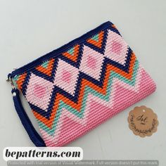 a pink and blue purse sitting on top of a white table next to a tag