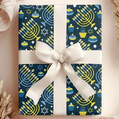 a gift wrapped in blue and yellow with a white bow on it, surrounded by festive decorations