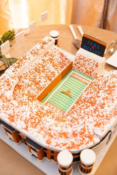 a cake shaped like a football stadium with orange sprinkles