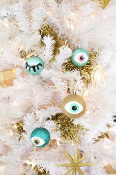 a white christmas tree with ornaments on it and gold stars around the branches, including an eyeball ornament