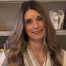 a woman with long hair is smiling for the camera while standing in front of shelves