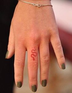 a close up of a person's hand with a small tattoo on her finger