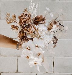 a woman holding a bouquet of flowers in her hand on a brick wall background,