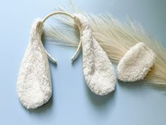 two white mittens are laying next to each other on a light blue surface,