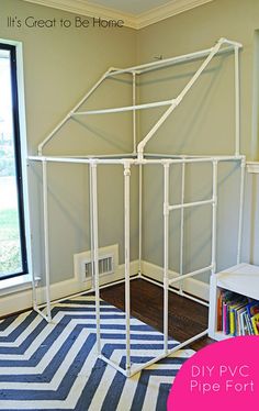 a white house made out of pipes in a room with a blue and white rug