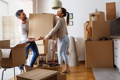 a man and woman moving boxes into their new home, one holding the other's hand