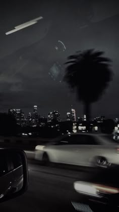 cars driving down the road at night with city lights in the background