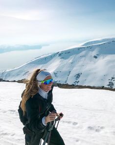 a woman on skis in the snow with mountains in the background