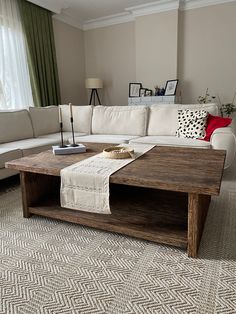 a living room with a couch, coffee table and other items on the floor in front of a window