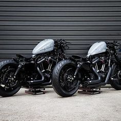 two black motorcycles parked next to each other in front of a garage door with roller shutters