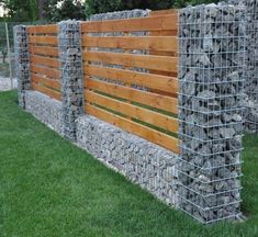 a fence made out of wood and metal wire with rocks on the top, along side it