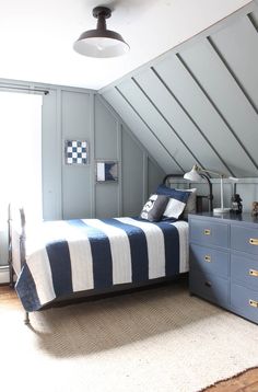 an attic bedroom with blue and white bedding, dressers and chest of drawers