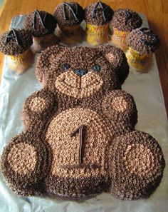 a cake shaped like a teddy bear with cupcakes around it