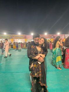 a man and woman standing next to each other in front of a crowd at night