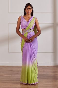 Lavender and green ombre pre-draped saree with pleated drapes, attached draped pallu and frill hem border. Paired with V neck padded blouse with all over pearl, sequin, cut dana embroidery and belt.
Components: 3
Pattern: Embroidered
Type Of Work: Pearl, Sequin and Cut Dana Work
Neckline: V Neck
Sleeve Type: Sleeveless
Fabric: Georgette, Opada Silk, Lining: Shantoon
Color: Purple,Green
Other Details: 
Floral cut work embroidered belt
Deep V back
Attached lining
Closure:
Saree: Side concealed zip Ombre Saree, Draped Saree, Saree And Blouse, Couple Wedding Dress, Simple Sarees, Drape Saree, Lavender Green, Unique Blouse, Purple Pearl