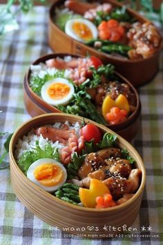 three wooden bowls filled with food on top of a checkered tablecloth covered table