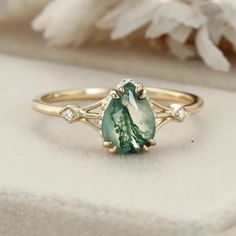 a close up of a ring with a green stone and diamonds on the side,