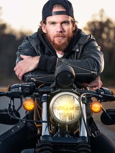 a man sitting on top of a motorcycle with his arms crossed