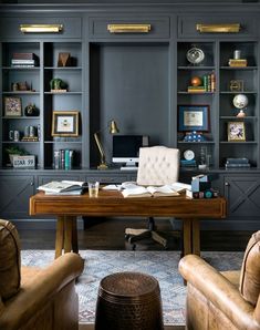 a home office with built - in bookcases and leather chairs, along with a desk