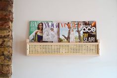 several magazines are displayed on the wall above a shelf with perforated wood pegs