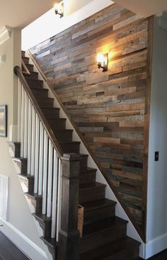 a wooden stair case next to a light on the wall