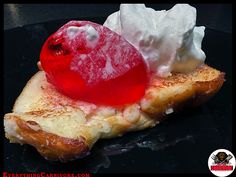 a piece of bread topped with whipped cream and jelly on it's side, sitting on top of a black plate