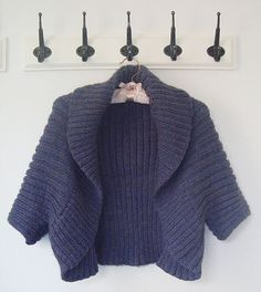 a blue sweater hanging on the wall with hooks and clothes pins in front of it